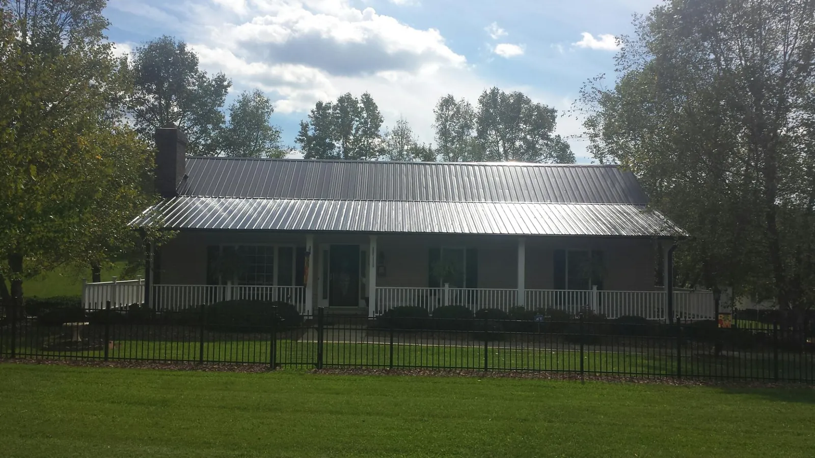 Gray metal roof on a brick ranch with a full width front porch — Gutter Guard Installation work by our crew in Waterford